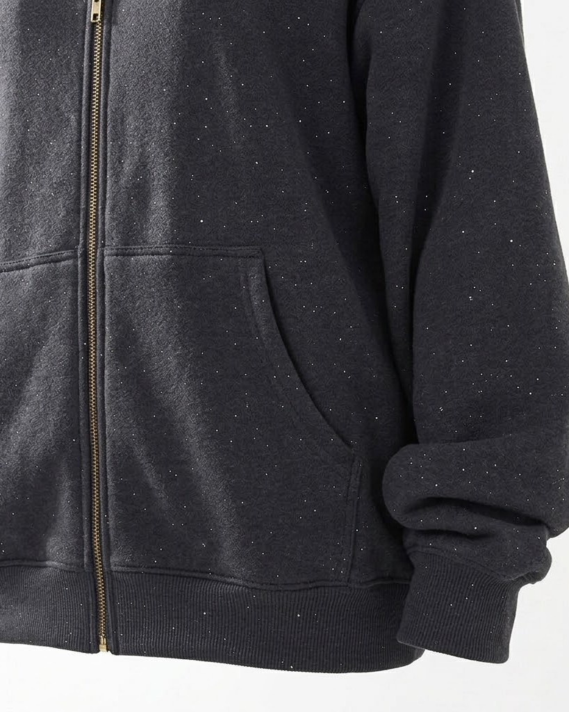Close-up of the dark grey hoodie kangaroo pocket, gold zipper and ribbed hem