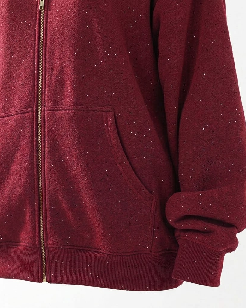 Close-up of the red hoodie kangaroo pocket, gold zipper and ribbed hem